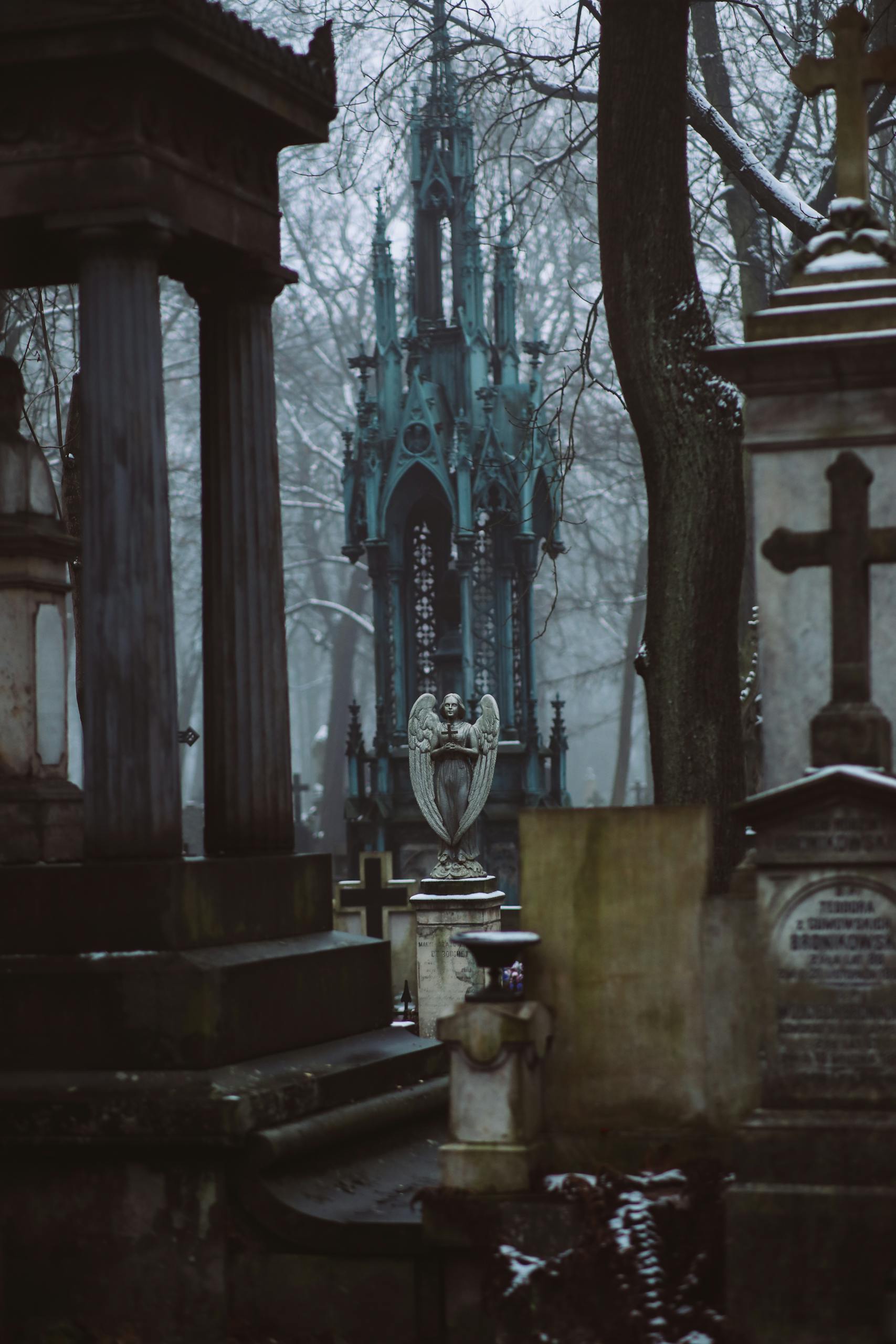 A moody cemetery shrouded in fog featuring gothic tombstones and angel statues.